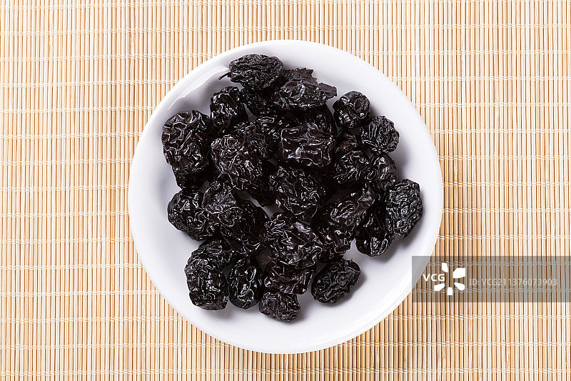 一盘乌梅摆放在竹席上特写图片素材