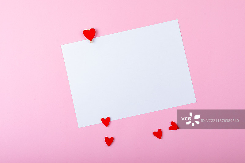 粉色背景上的空白白纸和红色小爱心图案，带复制空间图片素材