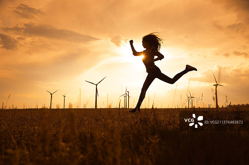 年轻女子在草原的夕阳下奔跑图片素材