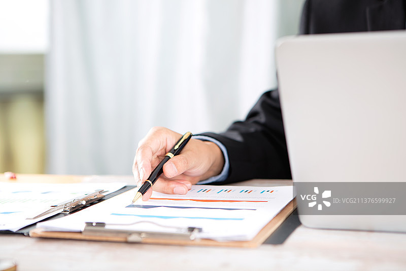 拿着笔的男性手指在商业图表上图片素材