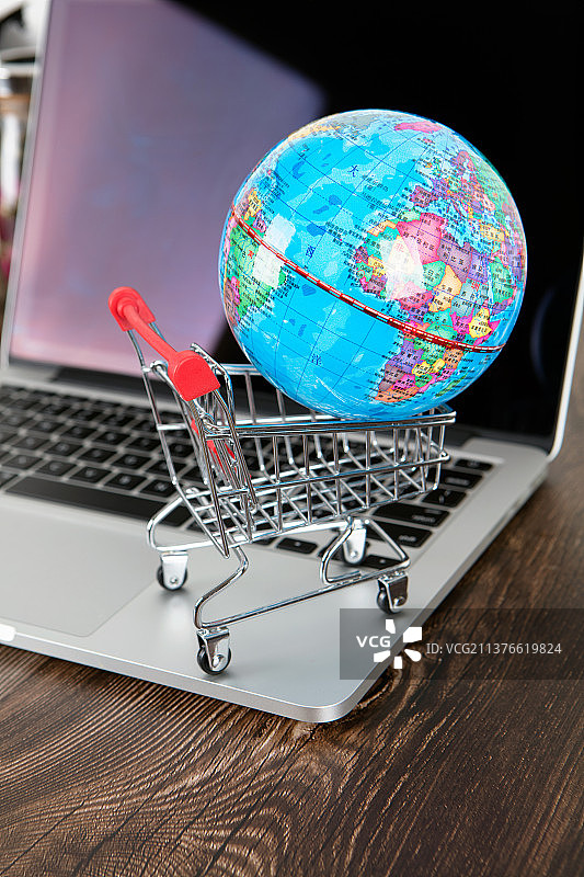 电脑上的购物车和地球仪图片素材
