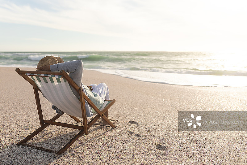 退休的混血老人在沙滩上坐在折叠椅上欣赏日落图片素材