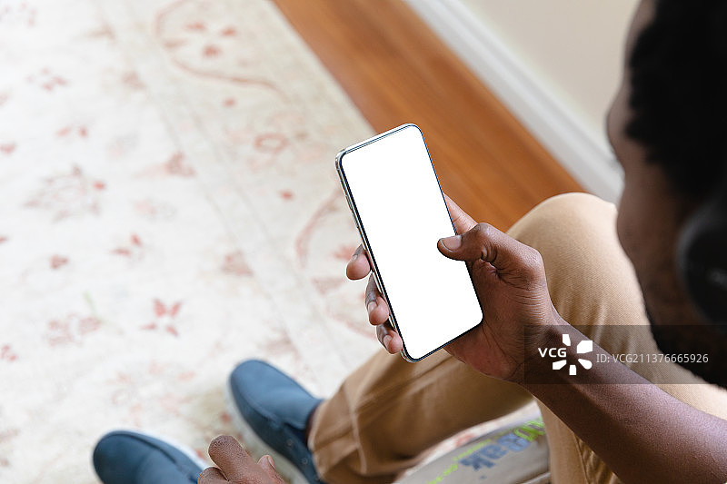 使用带有空白屏幕的智能手机，展示复制空间的年轻非裔美国男子图片素材