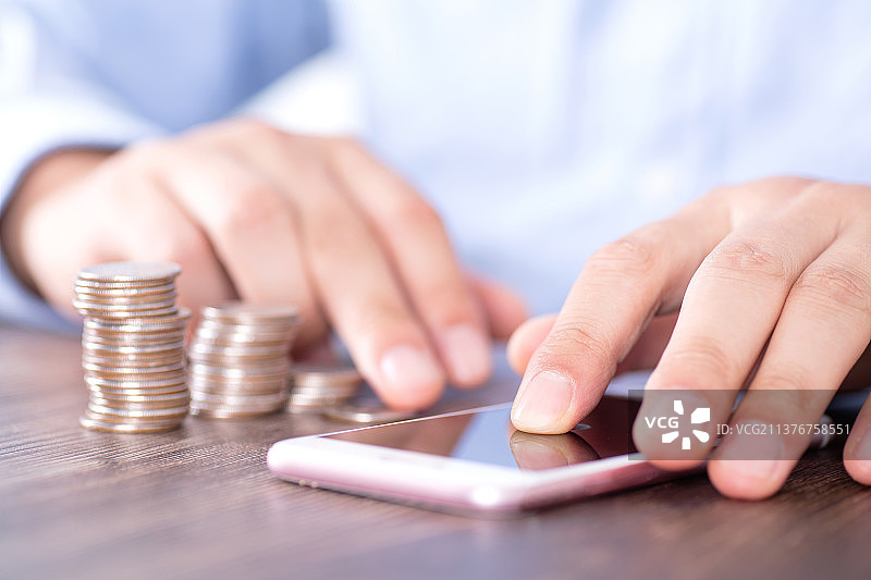 一堆硬币和旁边使用手机的人图片素材