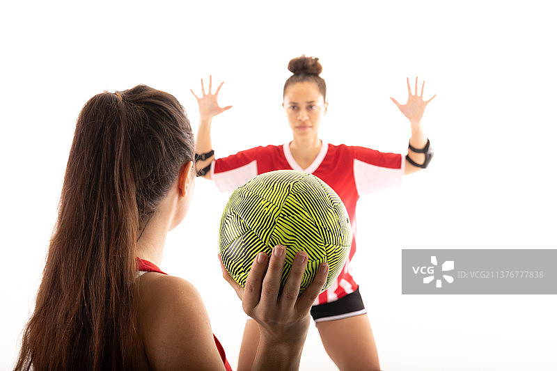 白人和混血年轻女手球运动员在白色背景下玩球图片素材