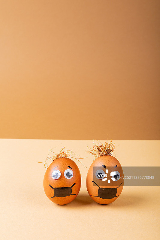橙色背景上的棕色复活节彩蛋，带有面具绘画和涂鸦眼睛图片素材