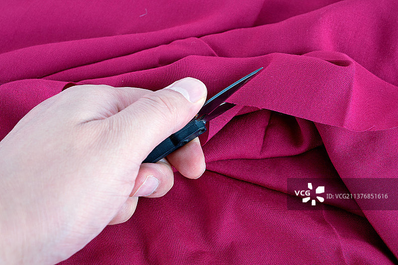 手拿剪刀裁剪布料图片素材