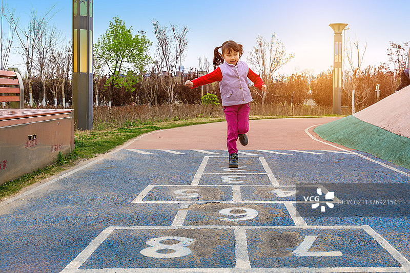 亚洲小女孩在游乐场里玩跳房子游戏图片素材