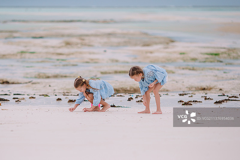 在热带海滩玩耍的两个快乐小女孩图片素材