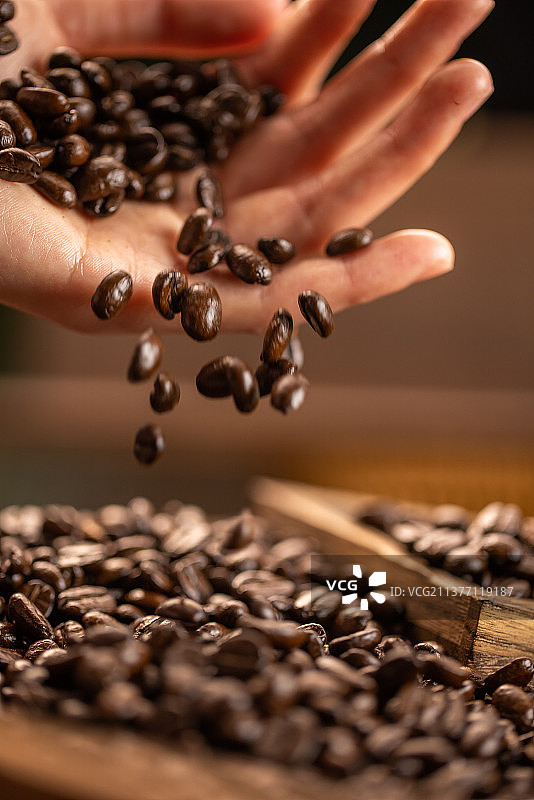 手拿咖啡豆抛洒掉落图片素材