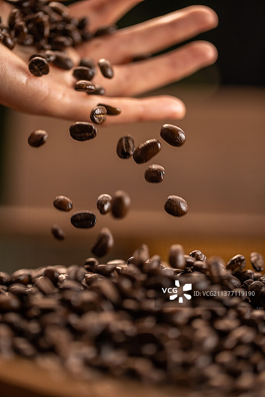 手拿咖啡豆抛洒掉落图片素材