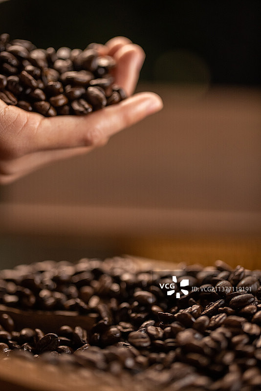 手拿咖啡豆抛洒掉落图片素材