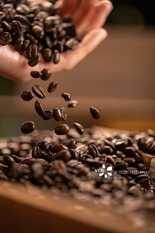 手拿咖啡豆抛洒掉落图片素材