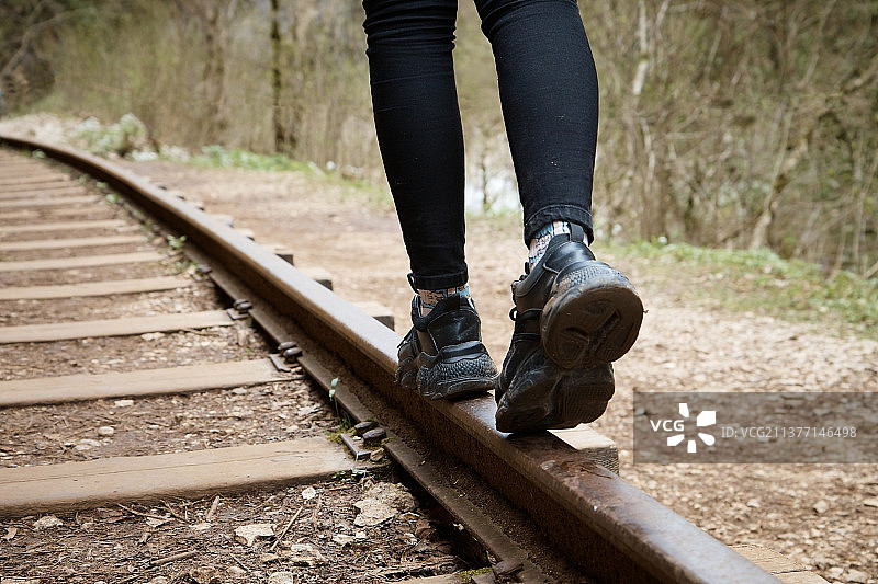 女孩在铁轨上行走特写，背景虚化图片素材