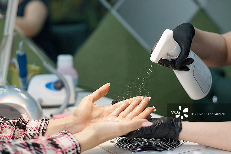 美容师在美容院用消毒剂护理患者双手图片素材