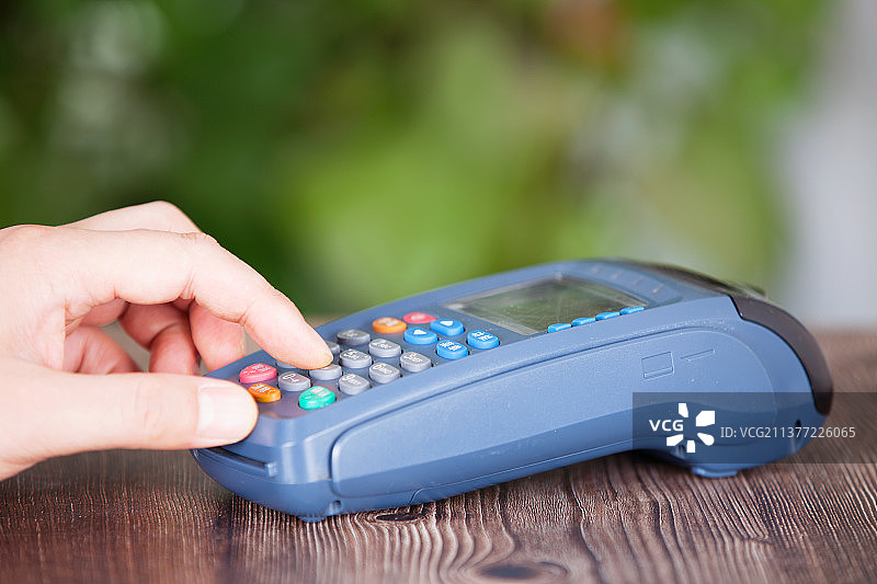 一只手正在pos机上输入收款金额图片素材
