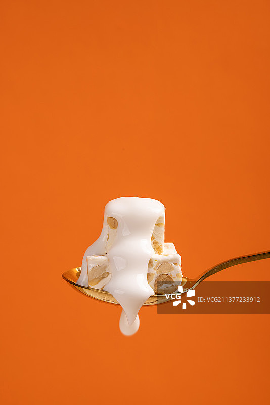 橙色背景下酸奶包裹的牛轧糖图片素材