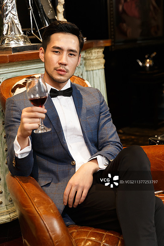 青年男人拿着红葡萄酒杯图片素材
