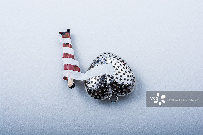 缠着绷带的微型男人雕像，连接在银色心形上图片素材
