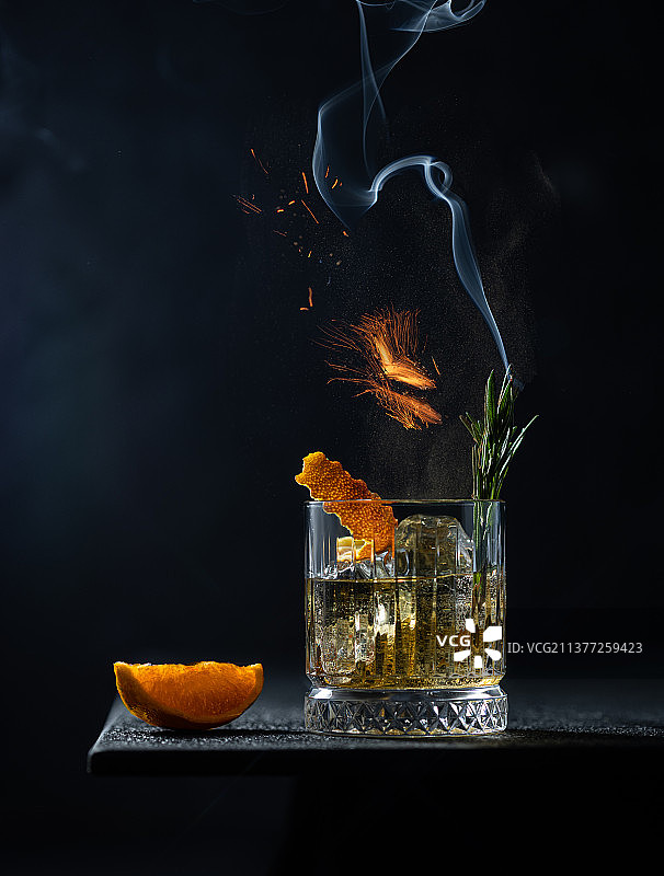 水晶杯中的威士忌或干邑，配以烟熏迷迭香、火焰和切片图片素材