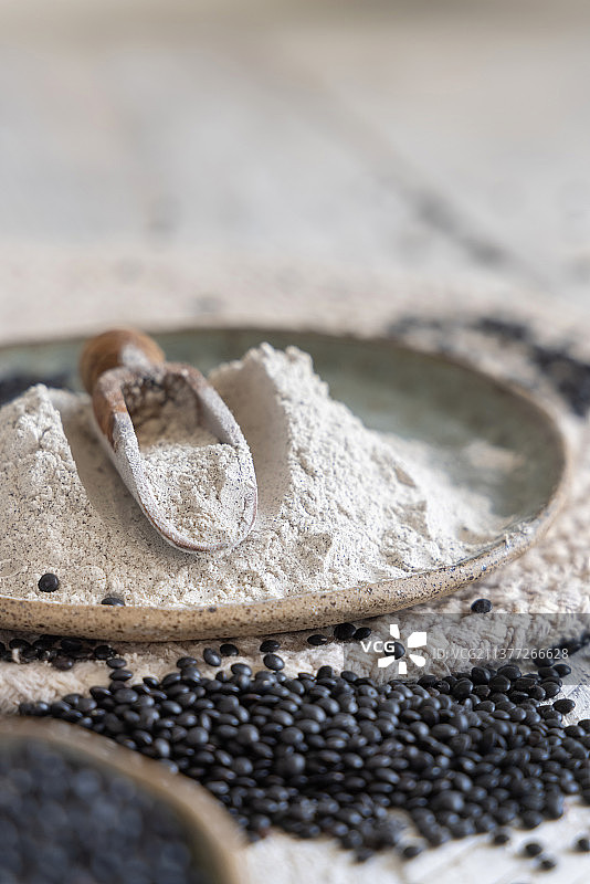 装有黑色小扁豆粉和豆子的盘子，配有木勺特写图片素材