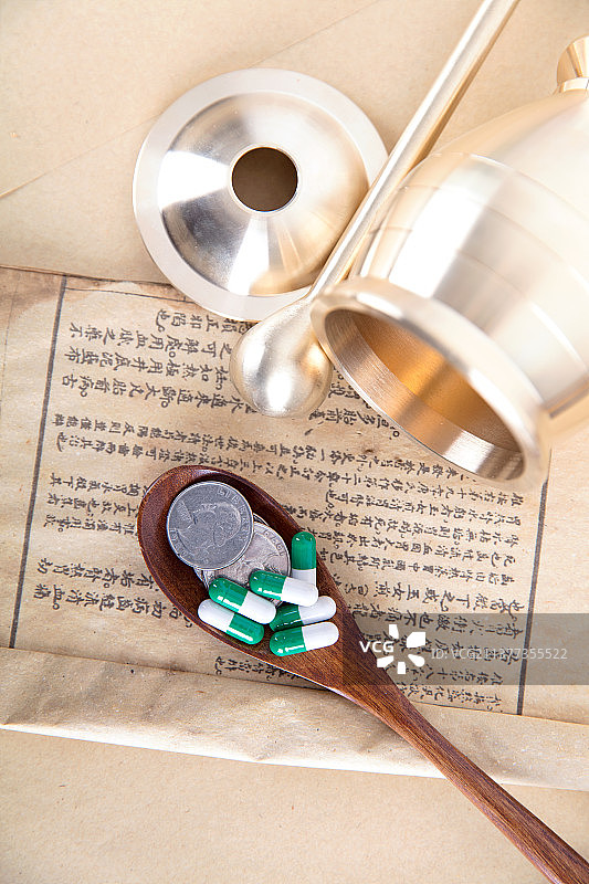 医书上一勺硬币和胶囊及一个药杵图片素材
