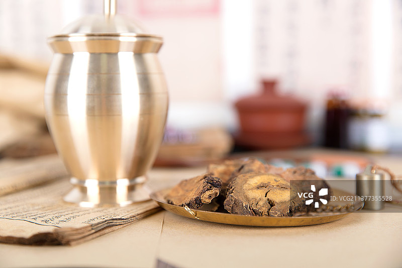 秤盘上的中药大黄和旁边的药杵及翻开的药书图片素材