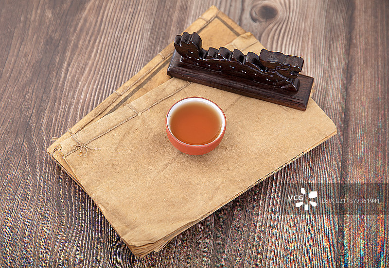 泛黄古书上的一杯茶和镇纸图片素材