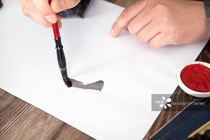 手拿毛笔在纸上练习毛笔字图片素材