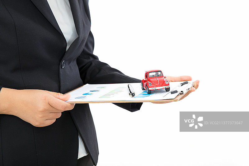 汽车销售人员手拿文件硬板夹和上面的小汽车模型图片素材