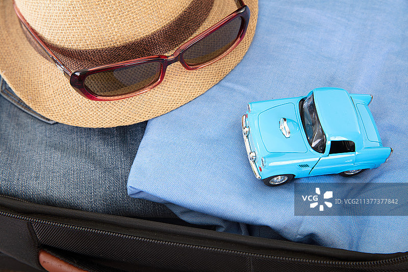 打开行李箱里的衣服和帽子及小汽车模型图片素材