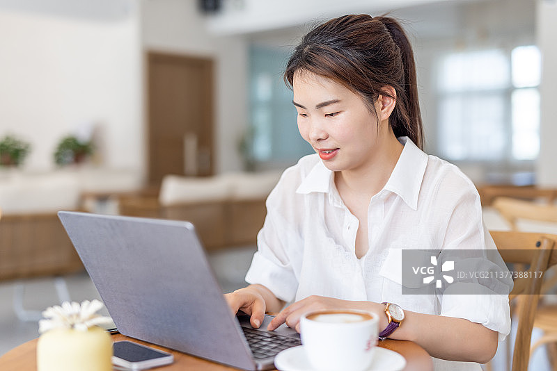 商务青年女子在咖啡馆使用笔记本电脑工作喝咖啡图片素材