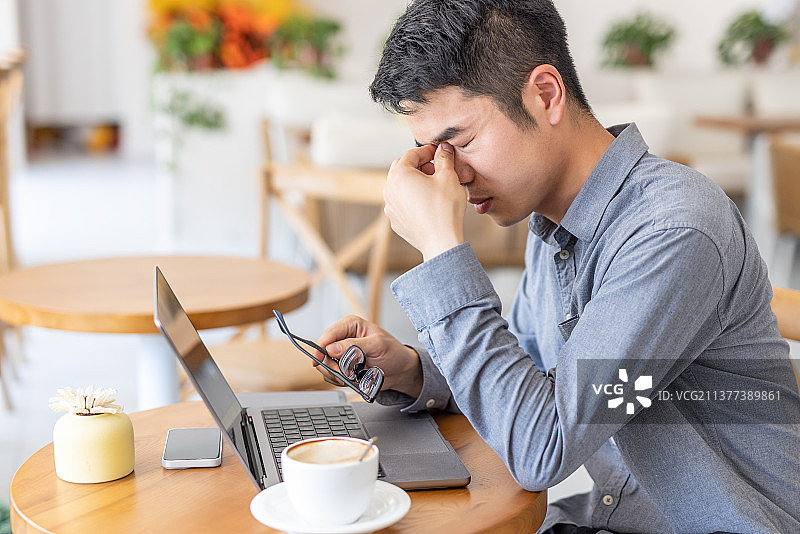疲惫劳累的亚洲人与笔记本电脑在咖啡馆工作图片素材