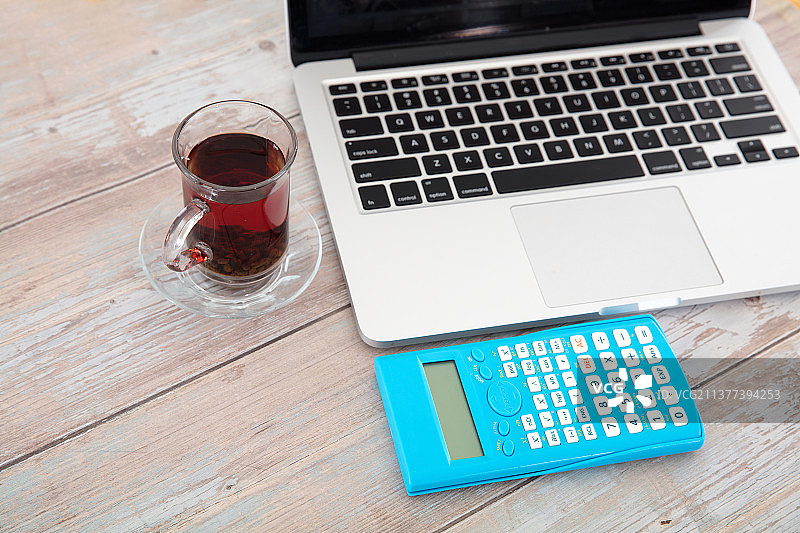 桌子上的笔记本电脑和一个计算器及一杯茶图片素材