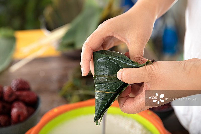 手中拿着一个刚刚包好的粽子图片素材