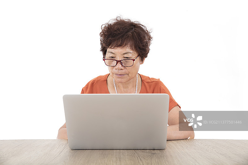 白背景前桌子旁的老太太正在学习使用电脑图片素材