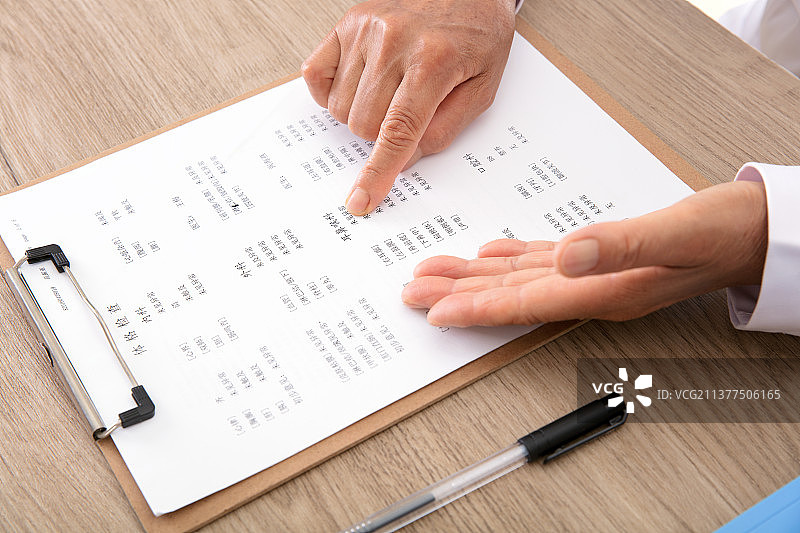 医生正在为患者介绍单子上的相关指标图片素材