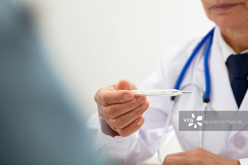 医生拿着测量完的体温计查看图片素材