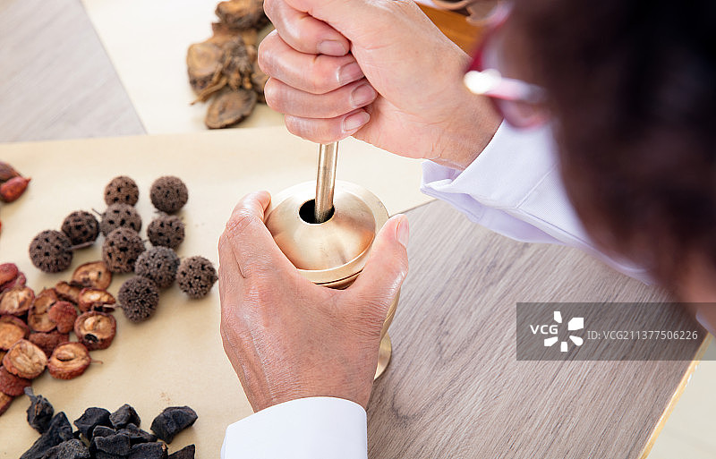 特写拍摄老中医正在使用药臼捣碎中草药图片素材