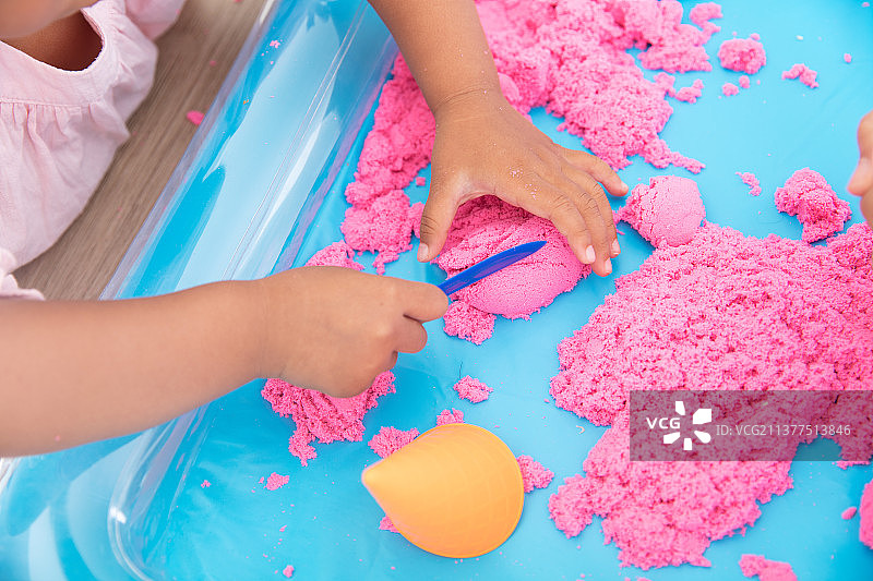 俯视拍摄小孩子在玩红色的太空沙图片素材