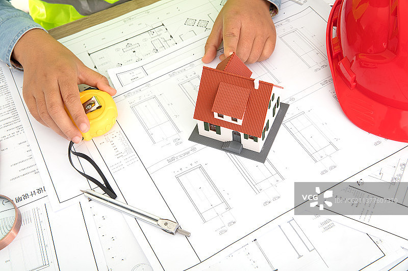 建筑师手指向放在图纸上的小房子模型图片素材