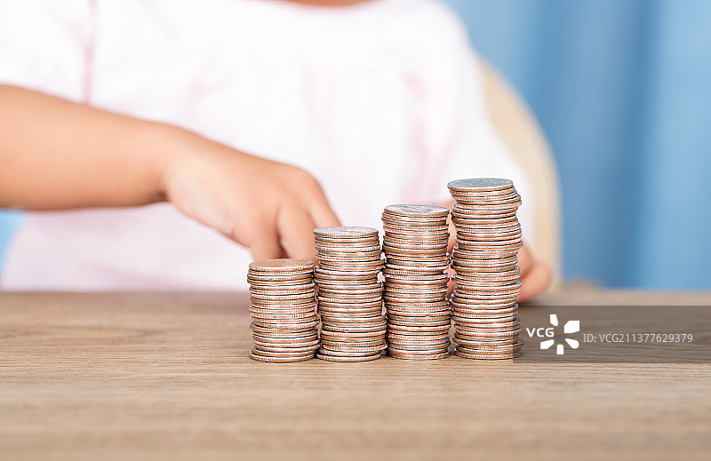 小孩子在摆放一排递增的美元硬币图片素材