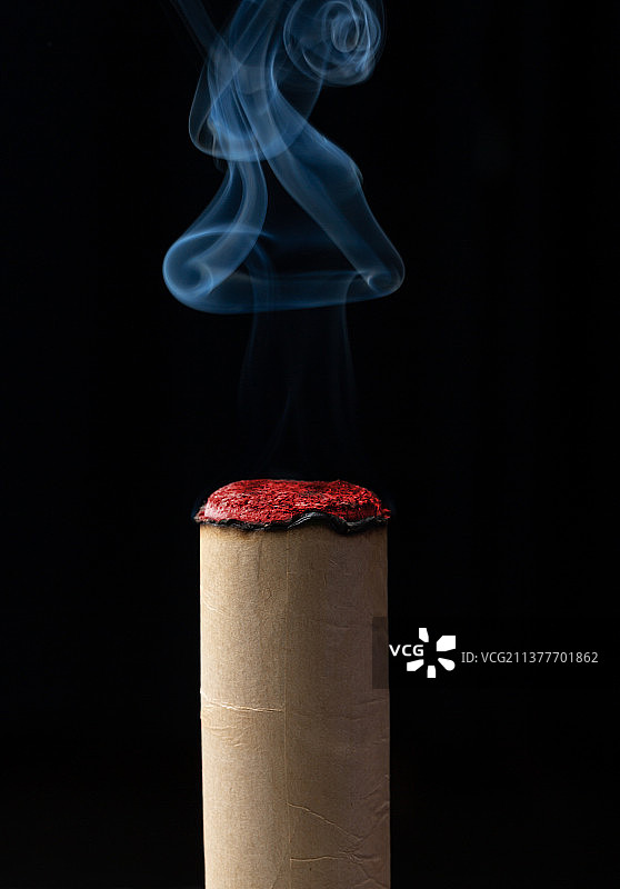 黑色背景前艾条升起的烟雾特写图片素材