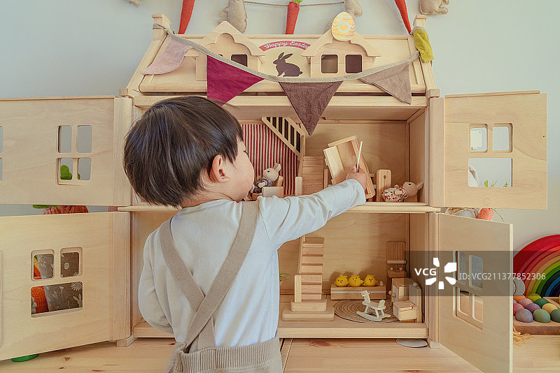 戴小兔子头饰的小男孩在布置复活节小木屋图片素材