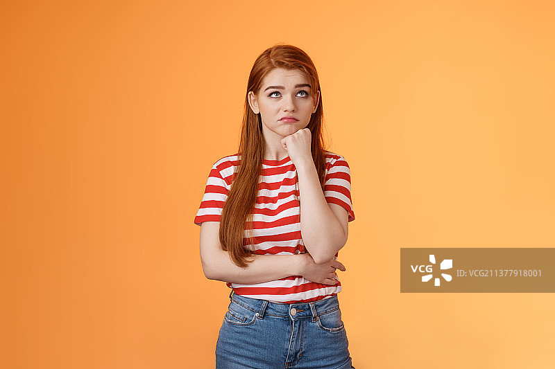 不开心的红发女子彩票中奖后感到不安和苦恼，抬头向上看图片素材