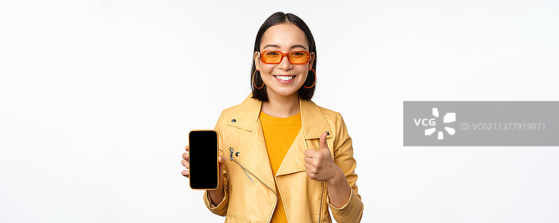 戴太阳镜的韩国女孩展示智能手机图片素材