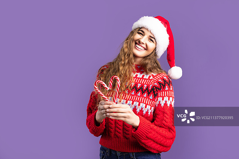 戴圣诞帽的快乐女孩用糖果摆出爱心紫色图片素材