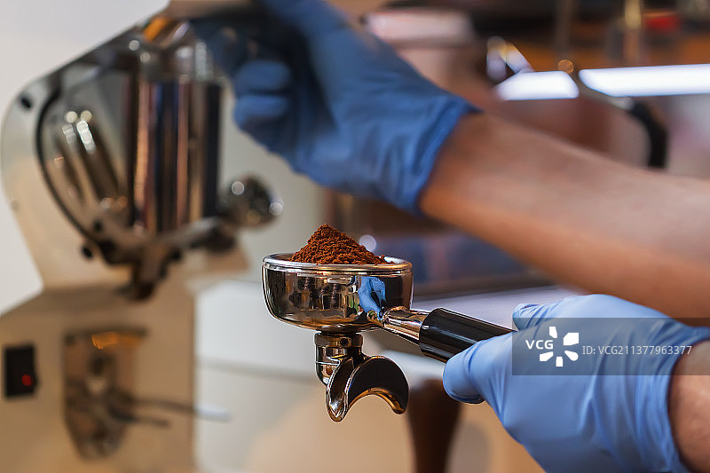 专业咖啡师在浓缩咖啡机中研磨新鲜烘焙咖啡特写图片素材