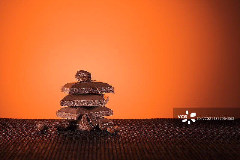 橙色背景下桌子上堆叠的牛奶巧克力特写图片素材