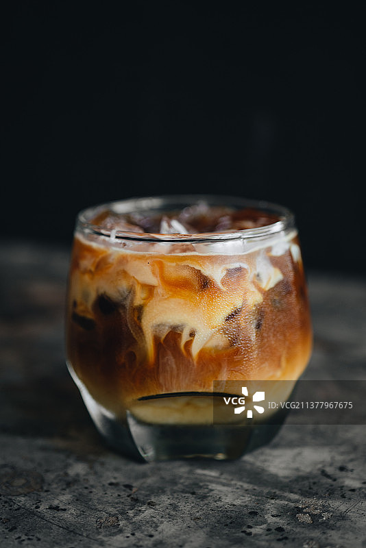 深色背景下玻璃杯中的牛奶冰美式咖啡图片素材